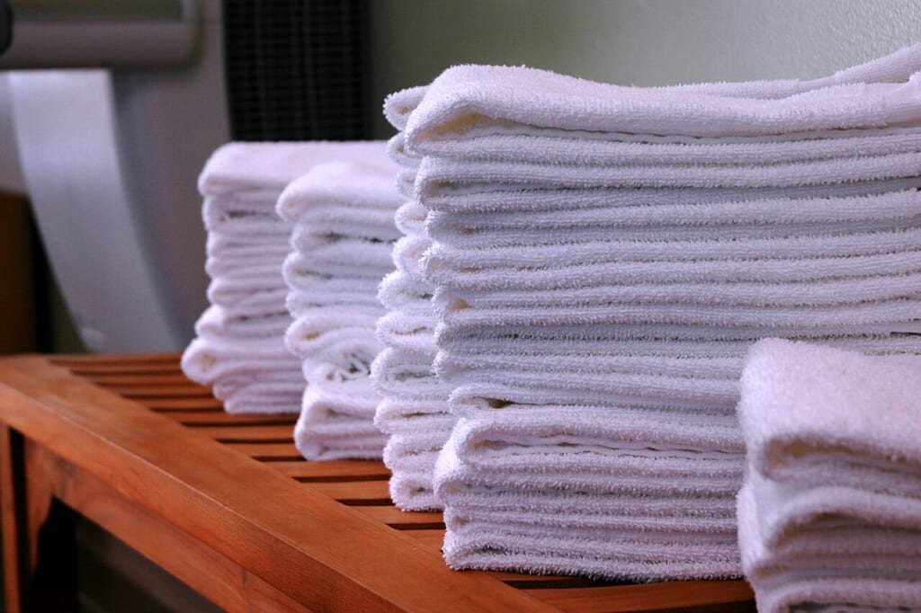 Stacksofgymtowelsonwoodbench | オンザショア立川店 立川駅徒歩1分年中無休の溶岩ホットヨガスタジオ 木のベンチに重ねたフェイスタオル 立川駅徒歩1分年中無休の溶岩ホットヨガスタジオ